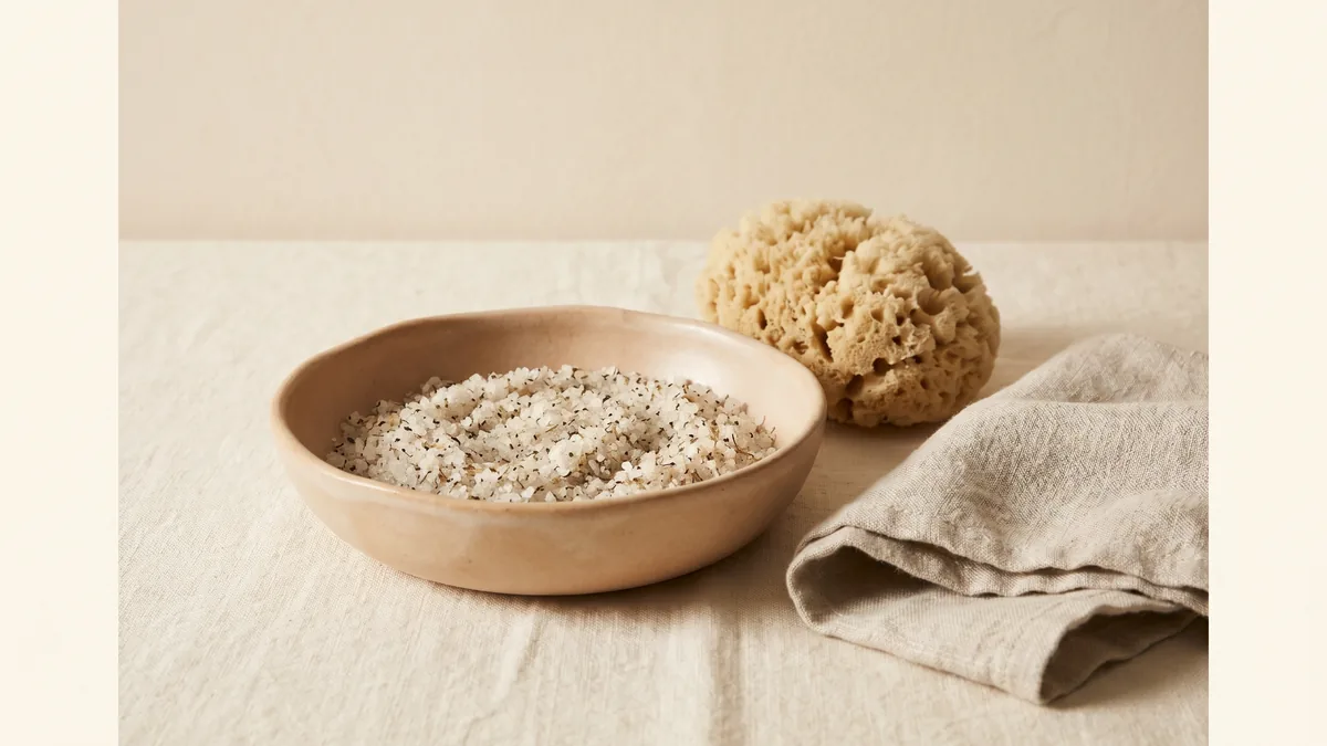 Un bol de ceràmica amb exfoliant i una esponja natural.